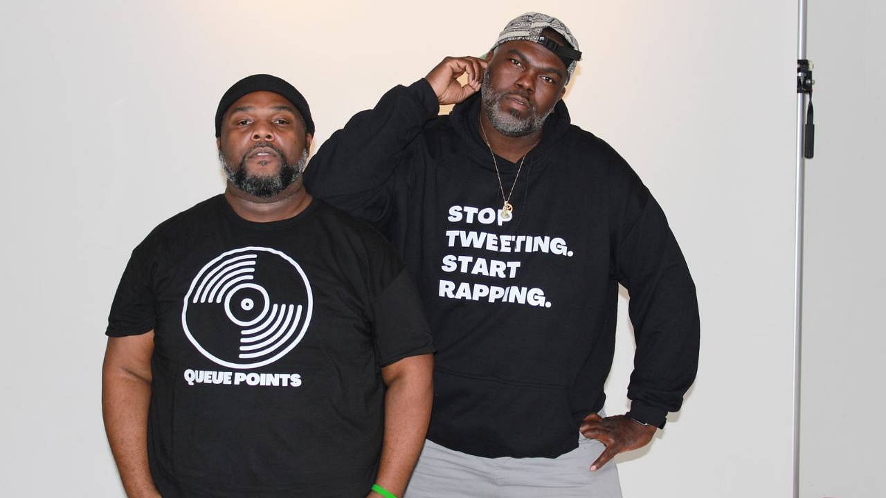 Color photo of Jay Ray (left) wearing a Queue Points logo shirt and DJ Sir Daniel (Right) wearing a stop tweeting start rapping shirt. Photography by Kyle Everett.