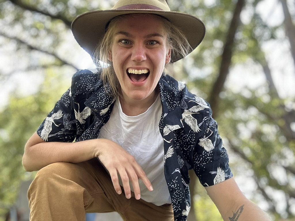 Photo of Rosie Burrows wearing an Akubra hat and leaning towards the camera with a huge grin on her face.